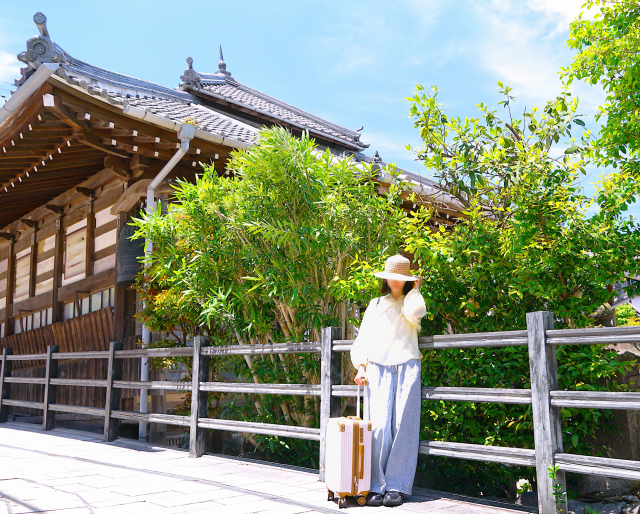 木造の建物の前に立つ人
